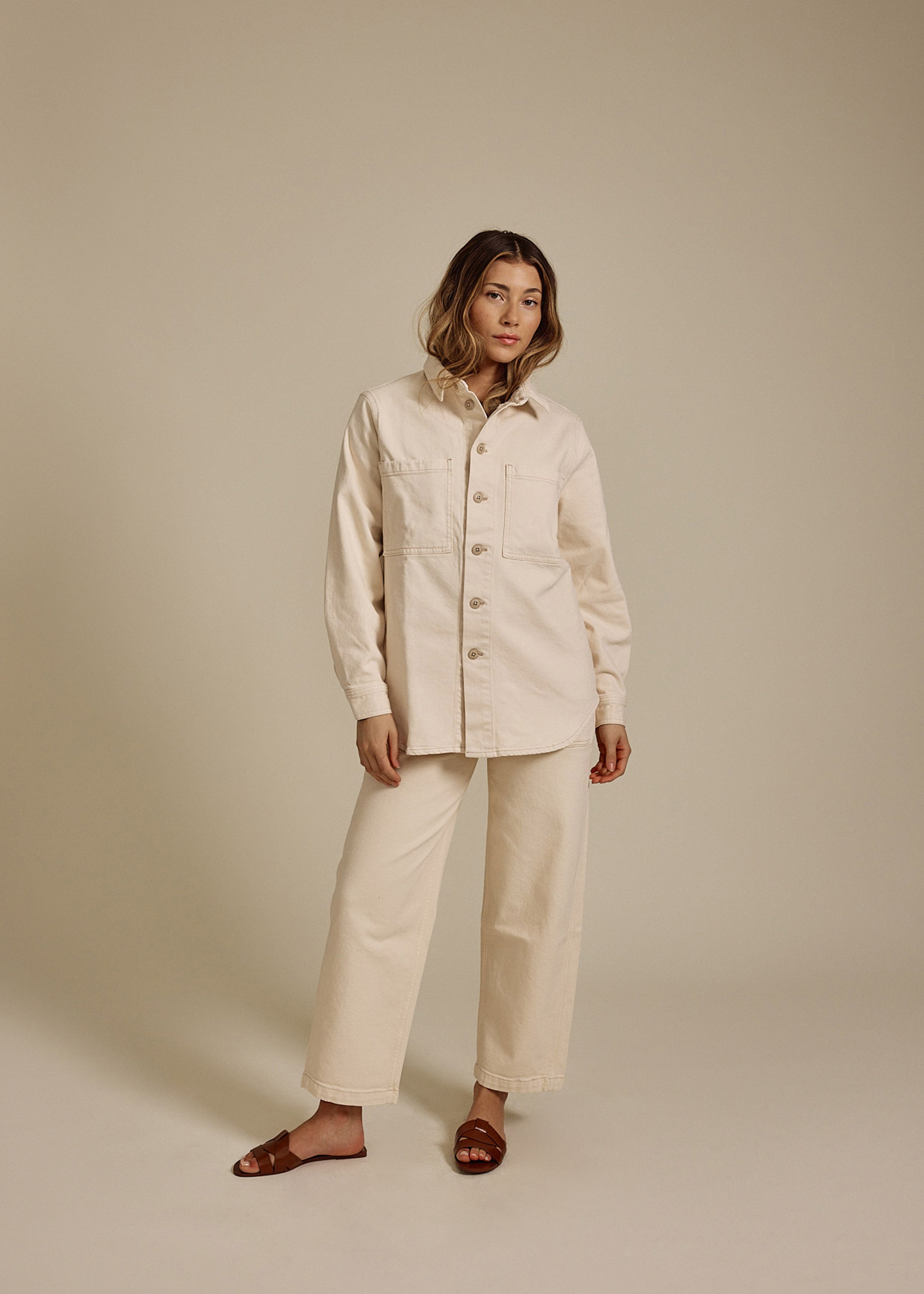 Model wearing high quality women's cropped jeans with a matching beige jacket and brown sandals