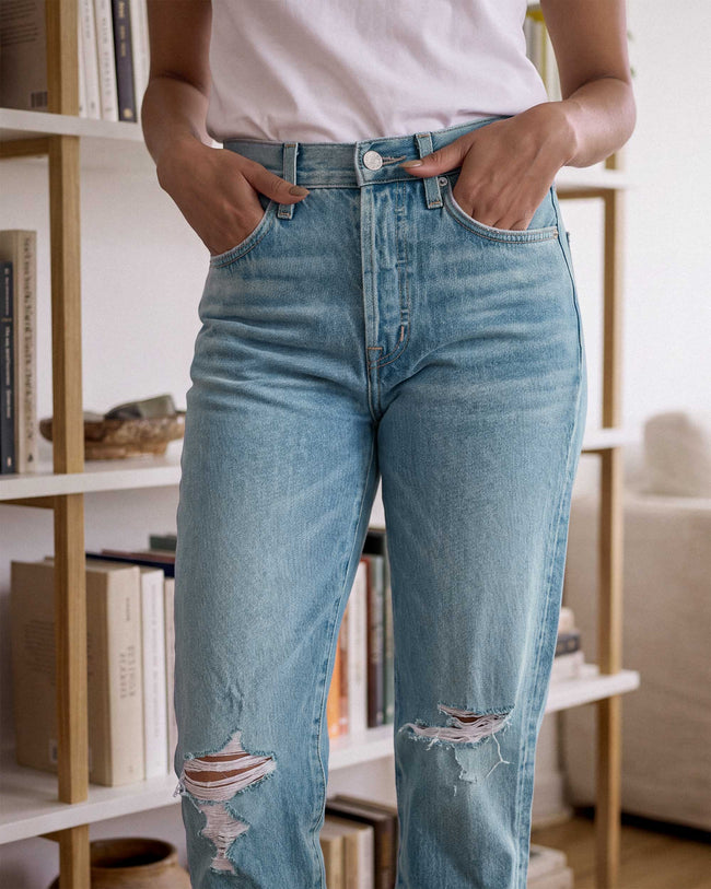 Light blue denim jeans with button fly and distressed knees at ankle length